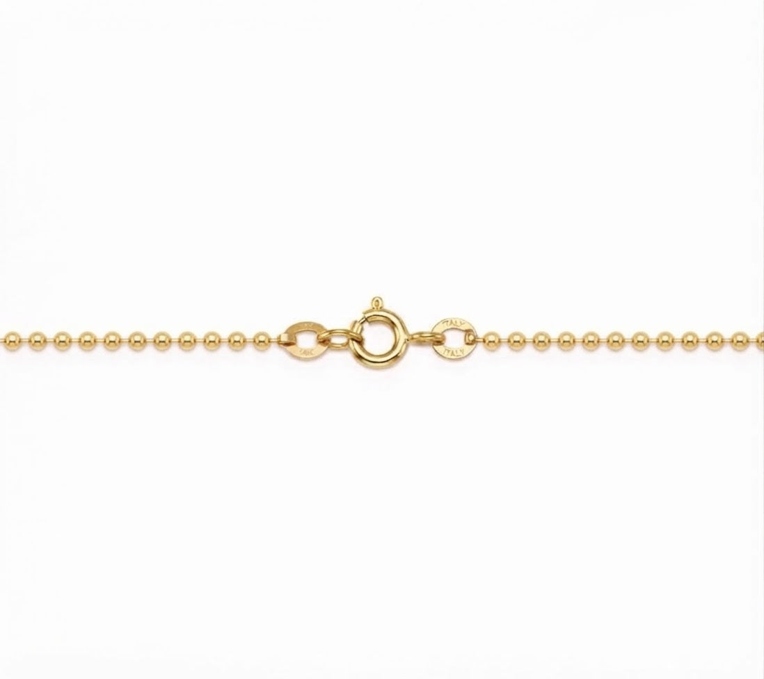 A close-up of a gold ball chain necklace showing the lobster clasp and a small circular brand engraving on a plain white background.